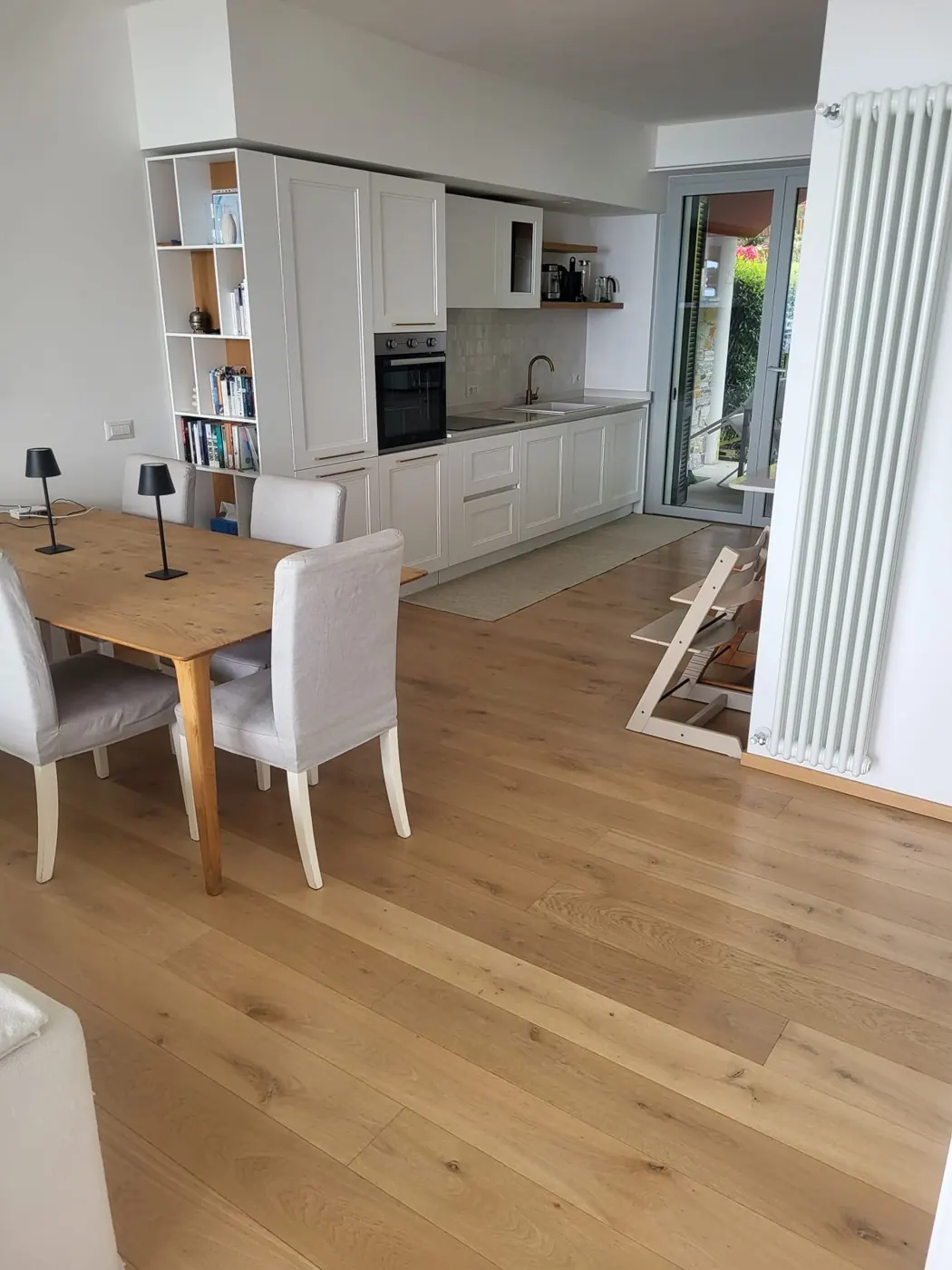 Dining table with linen chairs in front of the open white kitchen