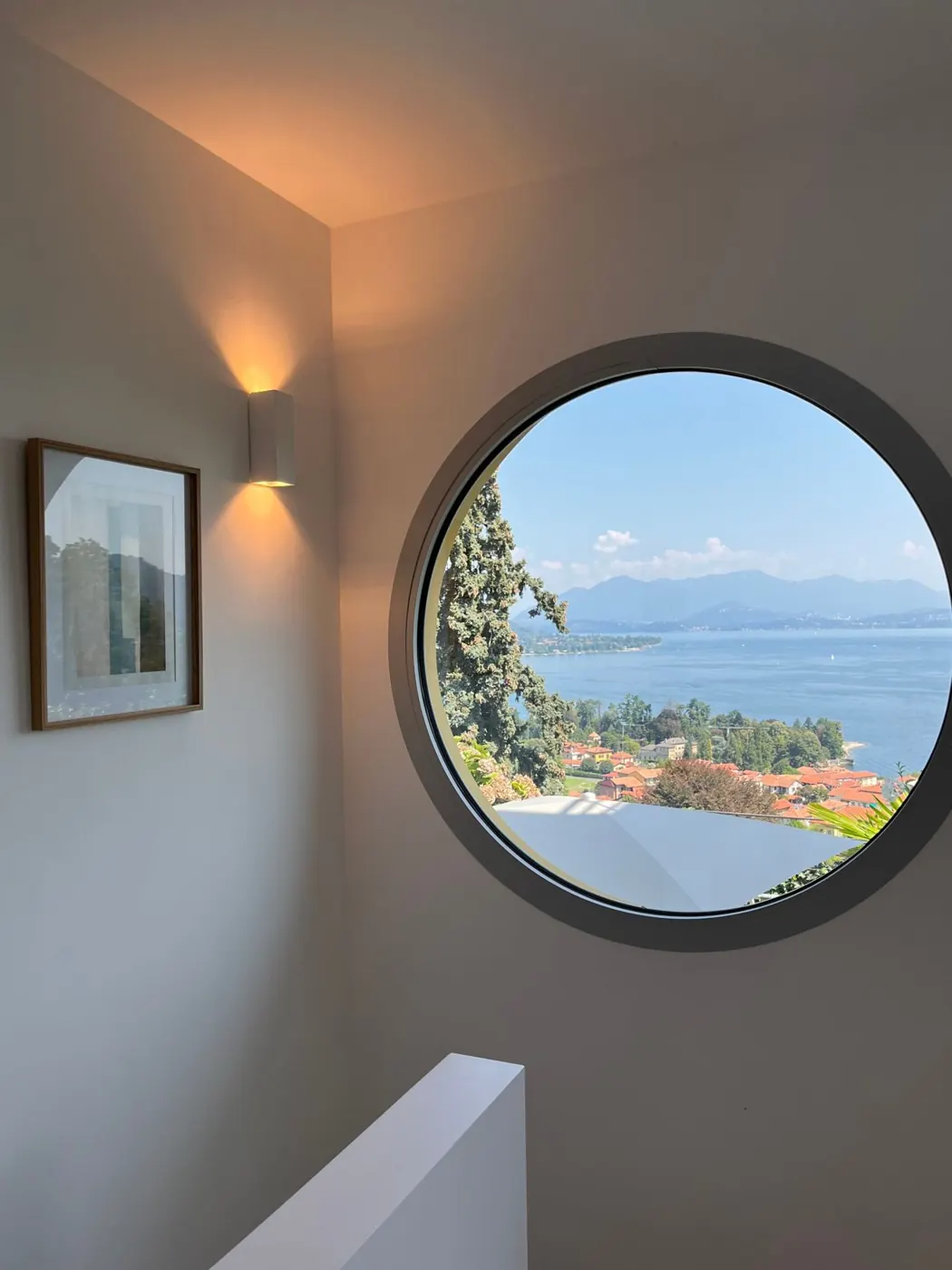 Round window on the staircase framing the lake and mountains